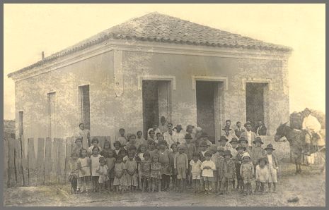 Fotografia de grupo de crianças defronte a casa situada no Largo da Matriz em Irapuã